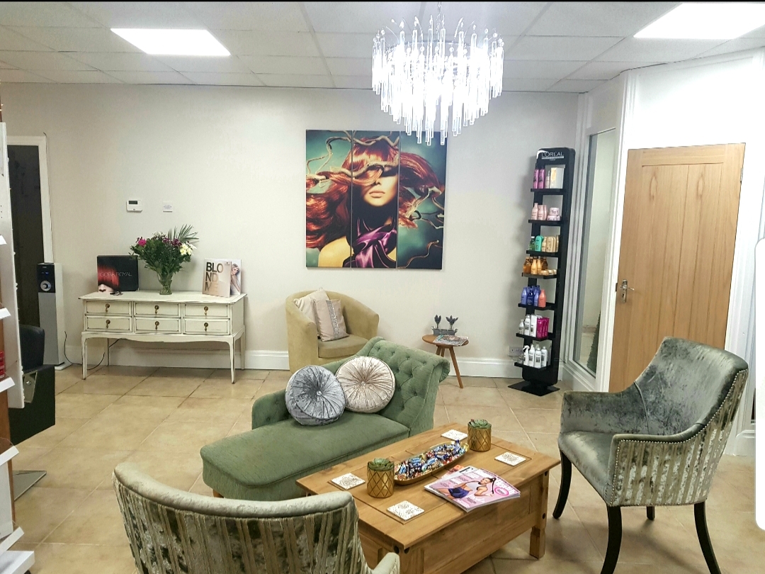 The earlier downstairs waiting area with a green chaise, velvet armchairs and wooden coffee table